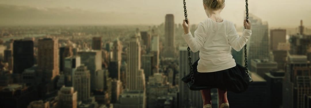Child on a swing overlooking a city skyline, capturing a sense of adventure and freedom in an urban environment.